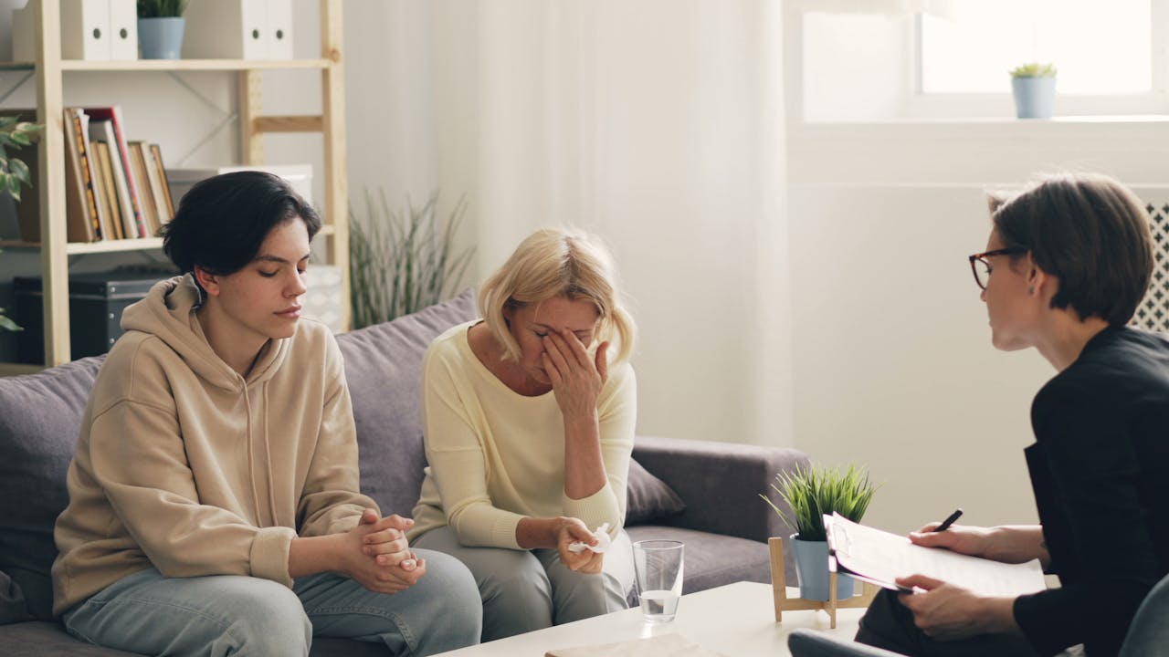 Emotional family therapy session with a therapist indoors, conveying connection and support.